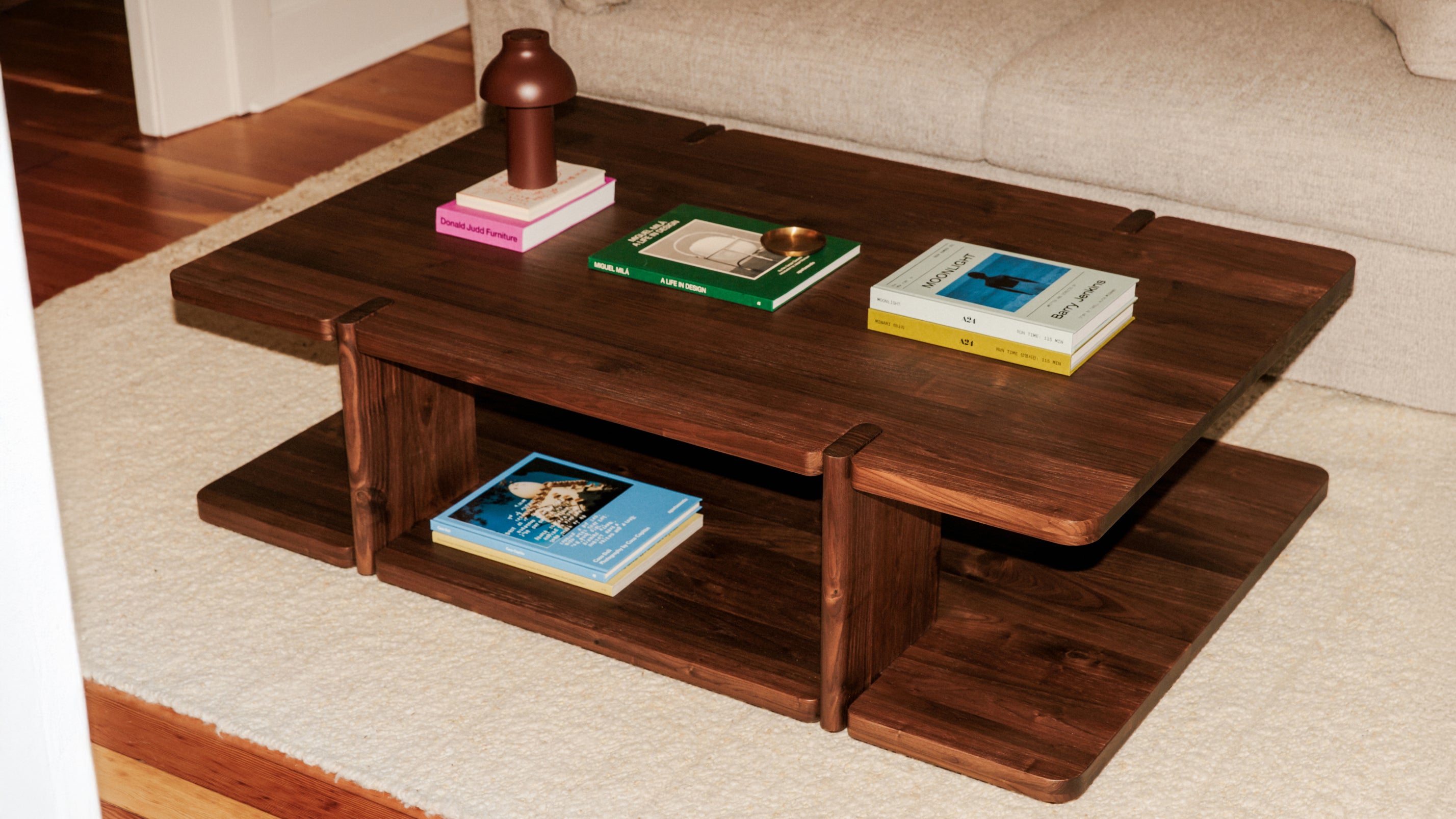 Wooden coffee table with books and a vase on top in a living room setting.